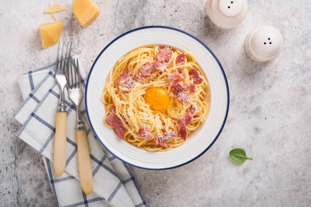 istock Carbonara pasta. Spaghetti with pancetta, egg, parmesan cheese and cream sauce on old gray concrete table background. Traditional italian cuisine and dish. Pasta alla carbonara. Top view. 1407533878