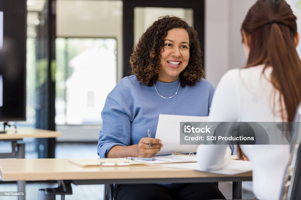 Office manager talks to the new intern The office manager holds onto a resume while speaking with the new intern they are considering. Interview - Event Stock Photo