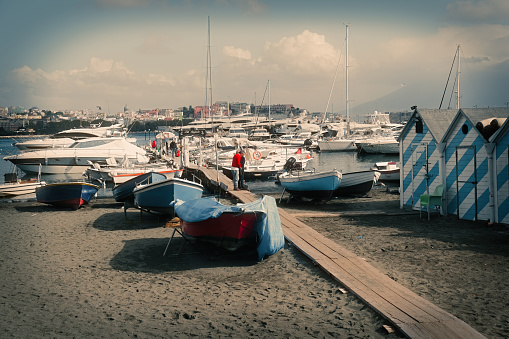 Naples, Italy - November 2, 2021. Urban landscape with boats and buildings on the Via Caracciolo , Gulf of Naples ( Lungomare di Napoli a Mergellina),  Mediterranean sea shore in Naples, Italy