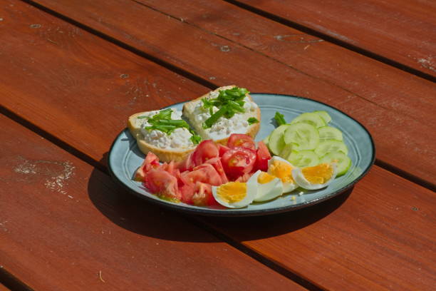 plate with eggs, tomatoes, cucumbers and white cheese on a wooden table