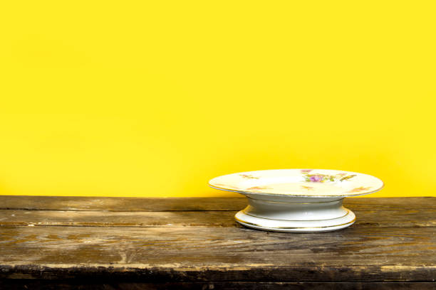 empty floral stand Cake on wooden table over yellow background