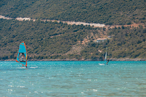 Little Girl Windsurfing on a Calm Day in the middle of the Bay - Stock Photo