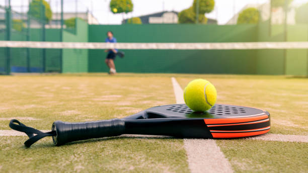 un hombre maduro caucásico jugando detrás de la red con pala de pádel y pelota amarilla - racketball racket ball court fotografías e imágenes de stock