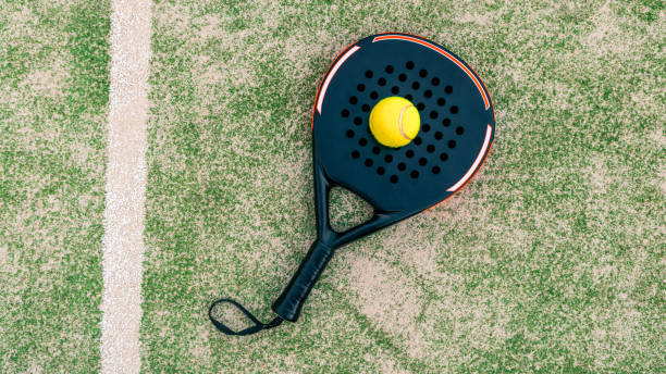 palla gialla in cima alla racchetta da paddle e dietro la rete sul manto erboso del campo verde - squash racketball sport exercising foto e immagini stock