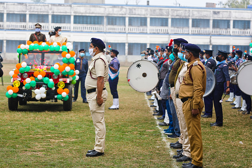 Katwa WB India - January 26, 2022 : Taken this picture in the town of Katwa in state of West Bengal on Republic Day Morning. In the picture police saluting to District Magistrate who hoisted the Indian Flag on school ground. In background are spectators witnessing the flag hoisting sitting on the top of the school building.