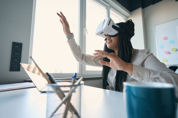 istock Joyous businesswoman wearing VR goggles in workplace 1407561558