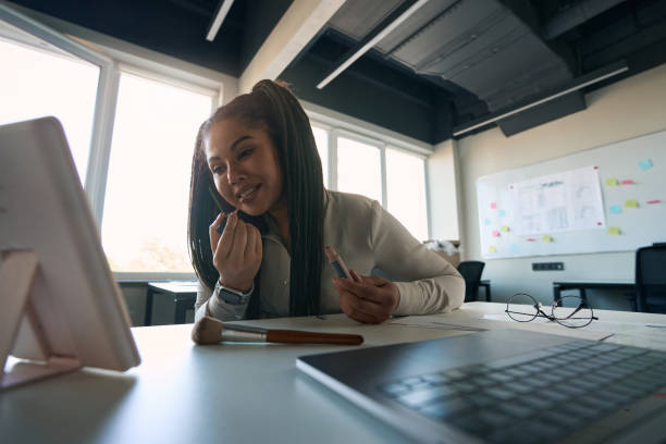 istock Joyous corporate employee putting on makeup during telephone conversation 1407561754