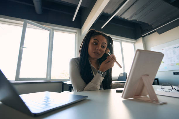 istock Concentrated office worker putting on makeup before cosmetic mirror 1407561756