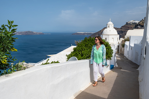 woman in elegant dress enjoying beautiful sea landscape from Santorini streets