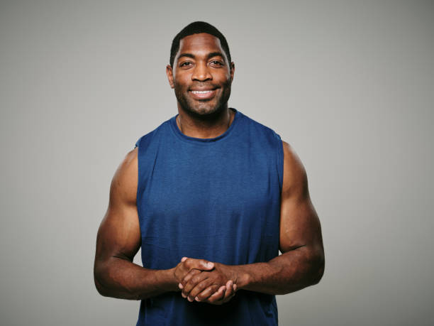 Handsome muscular body builder smiles as he raises his clasped hands triumphantly.