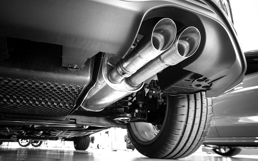 The exhaust system in the car seen from below, visible exhaust tip, the car is on the lift in the car workshop.
