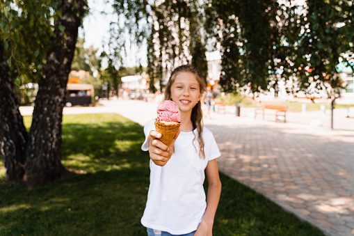 Funny child girl with ice cream cone in waffle cup. Summer sweets food. Creative advert for ice cream stand and shop