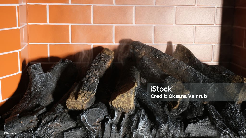 Fireplace with burnt wood. Brick firebox. Apartment Stock Photo