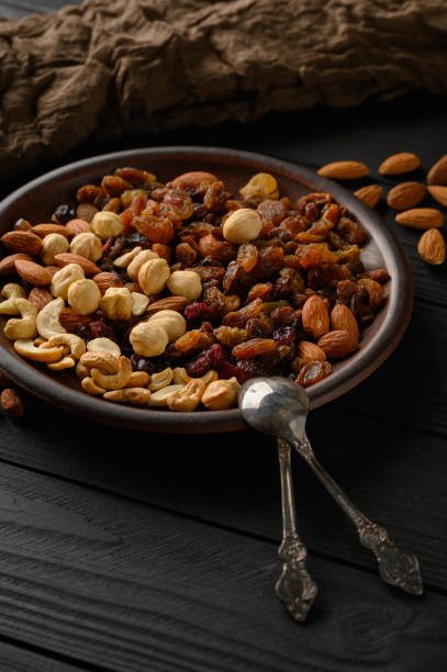 istock Hazelnuts, cashews, raisins, almonds, peanuts, walnuts on a wooden black background 1407571026