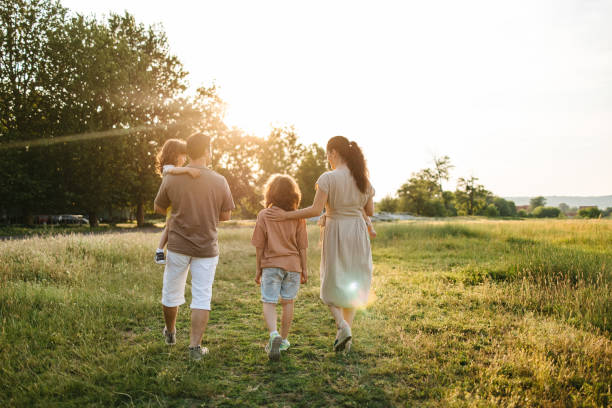 istock Family with three children walking on grass field 1407571135