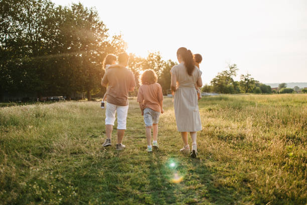istock Family with three children walking on grass field 1407571307