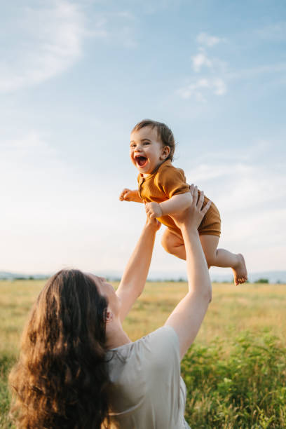 Mom holding her baby up in the sky stock photo