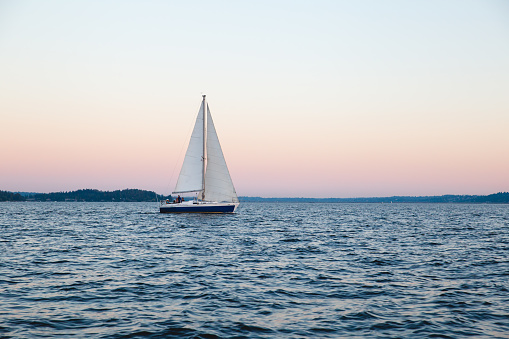 A sailboat floating at sunset on Union Bay in Seattle, WA.