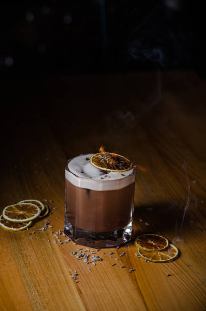 A glass with an alcoholic cocktail in a restaurant bar. Chocolate cocktail decorated with lavender, which is set on fire. A glass with an alcoholic cocktail in a restaurant bar. Chocolate cocktail decorated with lavender, which is set on fire. bailey castle stock pictures, royalty-free photos & images