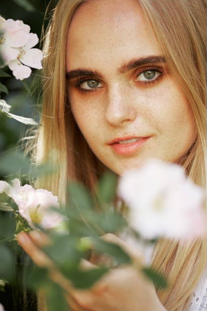 happy pretty blond girl with flowers looks at camera