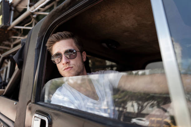 istock Handsome blond young man with stubble and sunglasses inside SUV. 1407582569