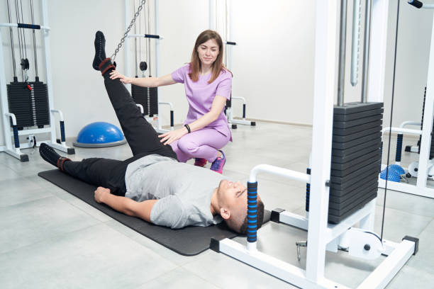 istock Man doing physiotherapy exercise with female doctor in clinic 1407584897