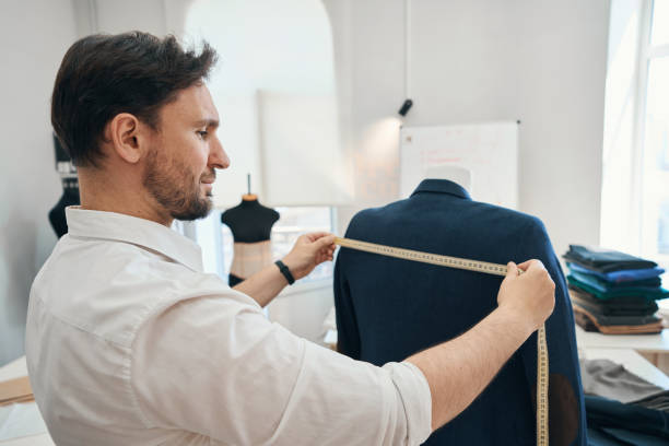 istock Man couturier measures length of jacket on a mannequin 1407590464