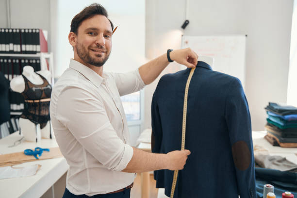 istock Man couturier measures ength of jacket on a mannequin 1407590471