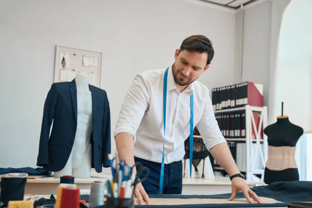 istock Couturier in sewing workshop applies a pattern to black fabric 1407590489
