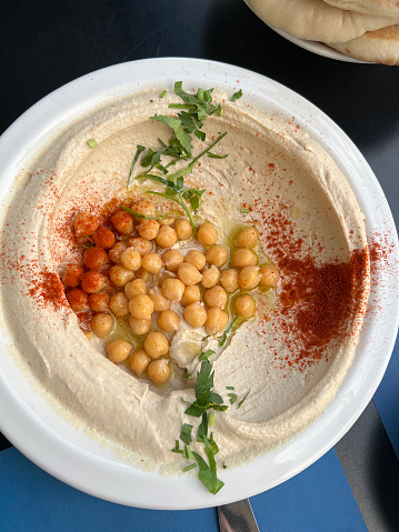 View from above of a bowl of freshly prepared hummus in Israel topped with chickpeas,  olive oil,  parsley, and paprika.
