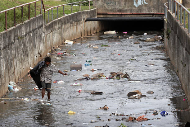 un récupérateur travaillant dans un cours d’eau extrêmement pollué - inhuman photos et images de collection