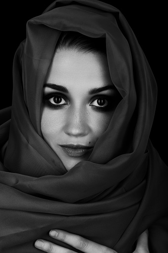 beautiful young woman with black headscarf over her face looking at camera, luxury makeup