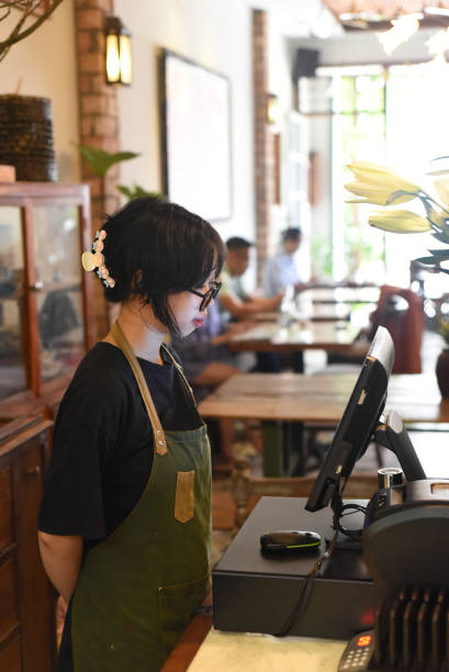 Young vietnamese waitress serving a customer at the checkout in cafe stock photo