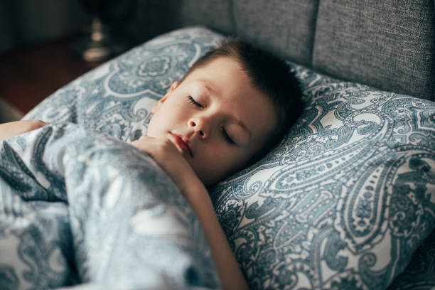 mignon garçon dormant dans le lit. enfant de 6-7 ans souriant, ayant de bons rêves. - 6 7 years photos et images de collection