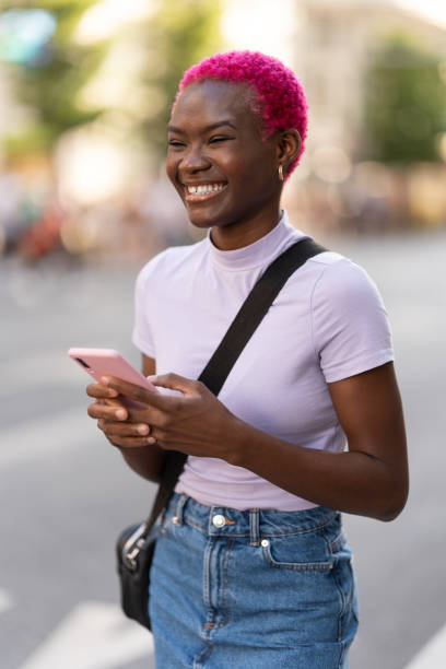 istock African young woman smiling while using the mobile outdoors 1407602615