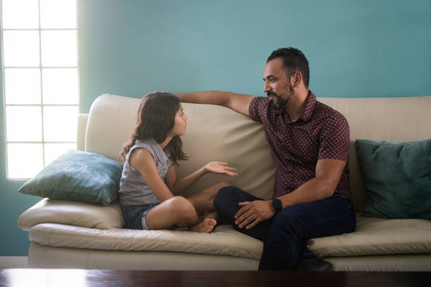 Father and daughter sitting on sofa and arguing A latin father and his young daughter sitting on the sofa at home and arguing face to face. kids and parents talk  stock pictures, royalty-free photos & images