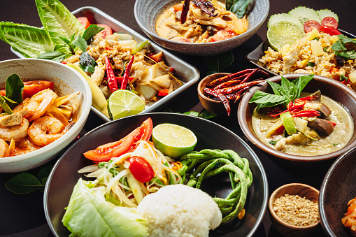 Delicious looking Thai foods on a black cloth table top.