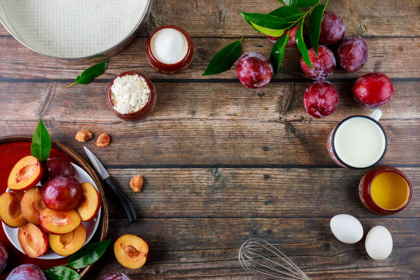 The ingredients of the baking process are eggs, whisk, plums, and a baking pan.