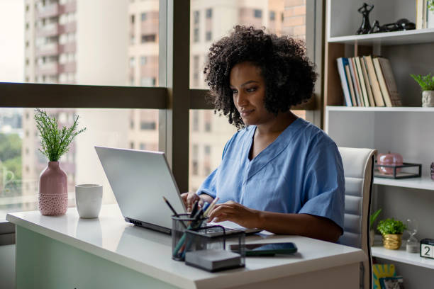 infermiera afroamericana che lavora sulla scrivania - laptop doctor using computer nurse foto e immagini stock