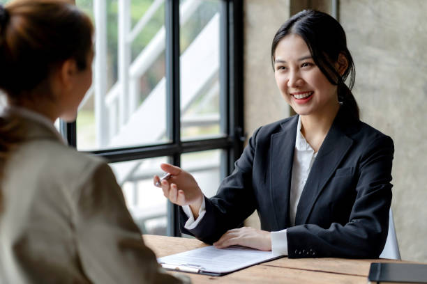 Smiling young Asian businesswomen talking to colleague and exchanging ideas  together at office. stock photo