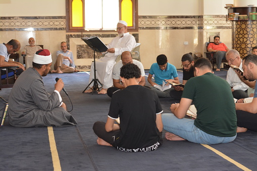 Cairo, Egypt, July 8 2022: A Noble Quran reading ring inside a mosque at the day of Arafah or Arafat before Eid Al-Adha, a group of people reading and learning Quran with an Islamic Imam or preacher