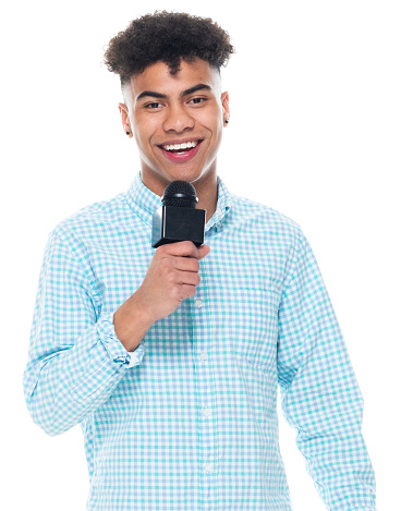 Presentador de noticias adolescentes de la Generación z de pie frente al fondo blanco con pantalones y sosteniendo el micrófono photo