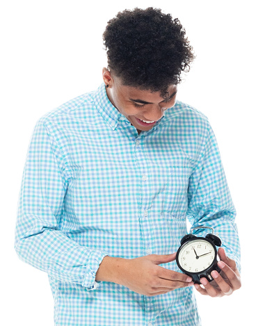Portrait of aged 18-19 years old with black hair african-american ethnicity boys in front of white background wearing shirt who is checking the time and holding clock