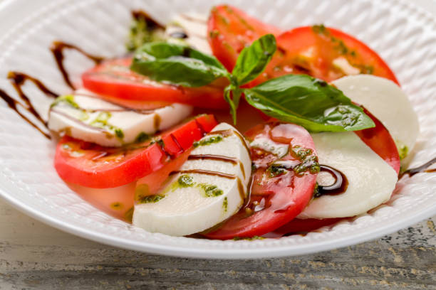 istock Caprese salad with mozzarella and tomato with basil and balsamic and pesto sauce on white plate macro close up 1407617231