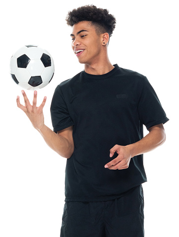 Waist up of aged 18-19 years old with curly hair african-american ethnicity teenage boys athlete spinning in front of white background wearing sports shoe who is in concentration and holding soccer ball and playing soccer - sport and using sports ball