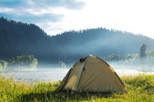 Tourist tent on river bank. Camping tent near mountain river. Local tourism, weekend at nature.