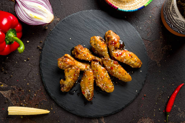 Chicken wings in sweet chili sauce on black stone plate top view Chicken wings in sweet chili sauce on black stone plate top view sticky sesame chicken sauces stock pictures, royalty-free photos & images