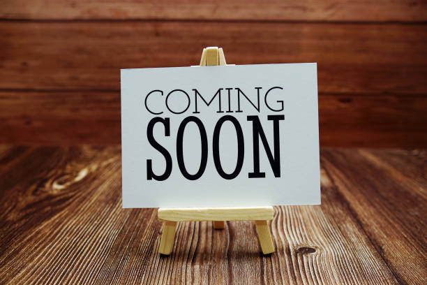 istock Coming Soon text on paper card on wooden background 1407622143