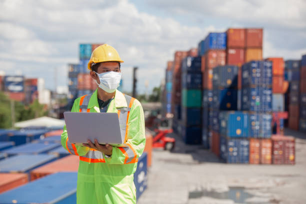 istock worker standing in shipping container yard holding laptop with smile. Import and export product. Manufacturing transportation and global business concept. 1407626492