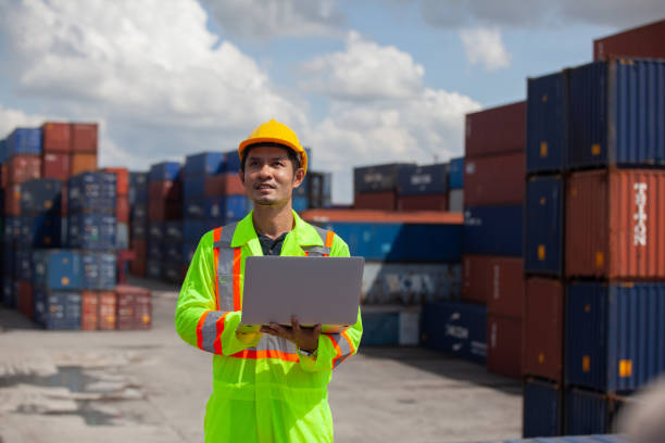 istock worker standing in shipping container yard holding laptop with smile. Import and export product. Manufacturing transportation and global business concept. 1407626515